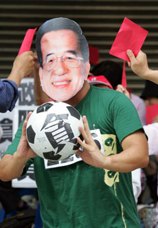 A demonstrator wearing a mask of Taiwan's President Chen Shui-bian and holding a soccer ball with the word which means "corrupt" is shown red cards by other protesters in Taipei, June 13, 2006. Taiwan's parliament launched a motion to oust Chen on Tuesday, turning up the heat on the president over a series of scandals involving his family and former aides. 