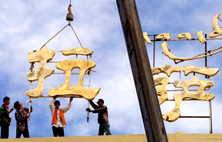 Chinese workers install the sign on the roof of Lhasa Railway Station in Lhasa, Tibet, June 20, 2006. The Chinese characters say "Lhasa." It was the largest railway station alongside Qinghai-Tibet Railway, which will begin trial operations on July 1.[Xinhua]