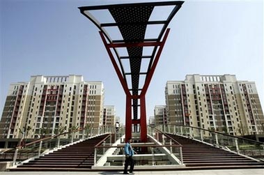 A man walks past newly built apartment complexes in Shanghai, China, Thursday, May 11, 2006 . China's efforts to slow its steamrolling economy from growth rates of 10 percent or more are being foiled by banks, companies and local officials who continue to pour investments into construction of luxury housing projects, shopping malls, showcase government buildings and factories. (AP Photo