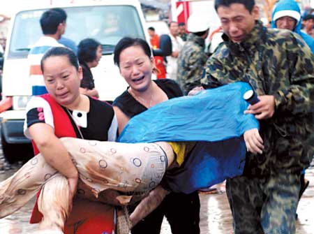 Distraught relatives and rescuers carry the body of a villager dug out from rubble in Jinxiang Township, Cangnan County in Zhejiang Province on Friday morning. Forty-three were killed when Typhoon Saomai ripped through the town. [Xinhua]