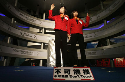 Humanoid robot 'Actroid DER' (L), produced by Japanese robotic venture Kokoro, waves with a local employee during a media preview of the Asia Robot Dream Exhibition at a shopping mall in Hong Kong November 24, 2006. 