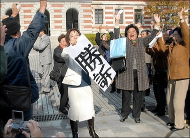 War orphans, who were Japanese children abandoned in China after the WWII, raise their hands to cheer as a supporter(C) shows a banner reading, 