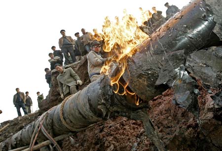 Workers repair a section of a natural gas pipeline in southwestern China's Chongqing municipality January 9, 2007. The pipeline was damaged when the road caved in, cutting off gas supply to about 300,000 people for seven hours, local media reported. Picture taken January 9, 2007. 