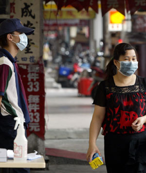 A masked fast food restaurant employee stands outside to take the temperatures of all customers in Taipei on May 14, 2003. The Taiwan authorities, struggling to contain the world's third-most seve