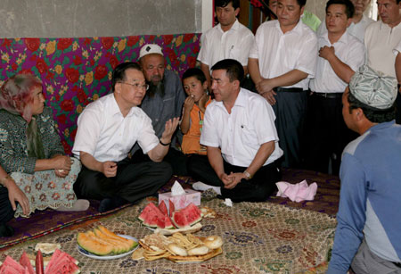 Chinese Premier Wen Jiabao (2nd L) talks with local people at a villager's home during his inspection tour to the northwestern Xinjiang Uygur Autonomous Region from last Thursday to Sunday. Wen Jiabao visited villages, schools, enterprises, hospitals and the Xinjiang production and construction corps of the army in a number of prefectures and cities to show his extensive care for local people's livelihood, education, medical service and the development of energy sources，Xinhua reported.[Xinhua]