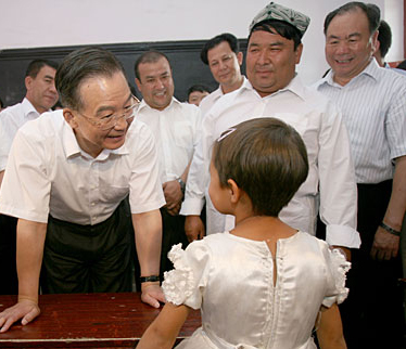 Chinese Premier Wen Jiabao (L) talks with a student at a bilingual kindergarten during his inspection tour to the northwestern Xinjiang Uygur Autonomous Region from last Thursday to Sunday. Wen Jiabao visited villages, schools, enterprises, hospitals and the Xinjiang production and construction corps of the army in a number of prefectures and cities to show his extensive care for local people's livelihood, education, medical service and the development of energy sources，Xinhua reported.Picture taken on August 16.[Xinhua]