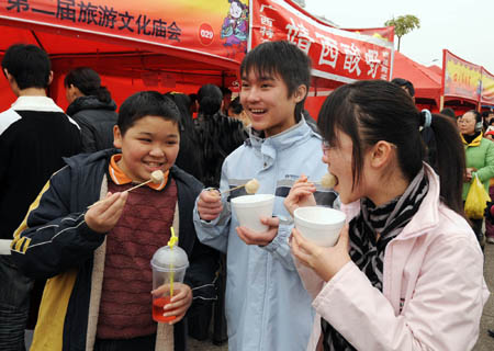 Three students eat Taiwan fish dumplings in Nanning, capital of South China's Guangxi Zhuang Autonomous Region, Feb. 10, 2008. Fish dumpling is a kind of cooked food in Southern China. It is made of fish meat with minced pork as the stuffing. The 2nd tourism temple fair of Nanning City opened on an ancient street called Yongzhou on Sunday. About 100,000 people attended the temple fair to taste various kinds of snacks from different places in the nation. [Xinhua]