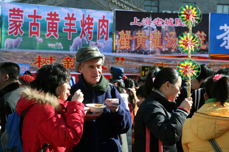 A foreign visitor tastes Beijing's traditional snack during Changdian temple fair in Beijing, capital of China, Feb. 11, 2008. Traditional entertainment activity is usually held at temple fair in China during Spring Festival.(