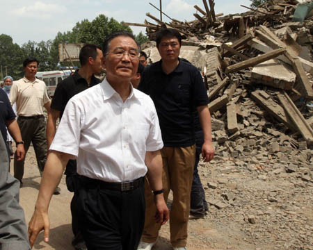 Chinese Premier Wen Jiabao (front) walks past debris during an inspection in Muyu Township, Qingchuan County, southwest China's Sichuan Province May 15, 2008. Qingchuan County is one of the worst-hit areas in Sichuan Province. Premier Wen is here to oversee rescue work and visit survivors. (Xinhua/Yao Dawei)