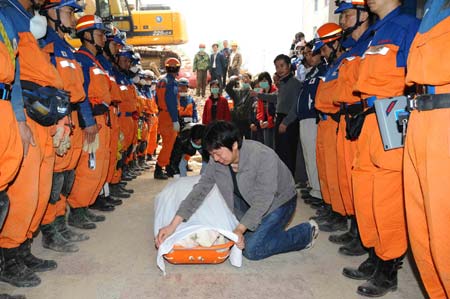 A man weeps by the body of his dead wife as members of the Japanese rescue team stand around him at Qiaozhuang Town of Qingchuan County in the quake-stricken southwest China's Sichuan Province, May 17, 2008. Japanese earthquake rescuers found two corpses in a collapsed six-floor building in Qiaozhuang at 7:25 am after 16 hours rescue operation. (Xinhua/Li Tao)