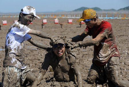 Tourists play with sea mud in E. China