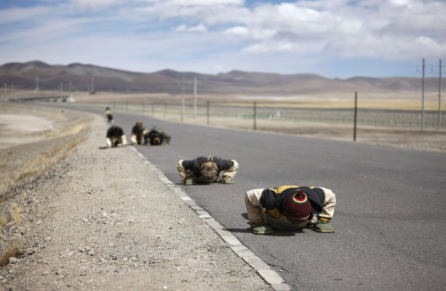 Tibetan pilgrims kowtow along a road