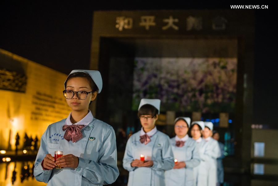 People hold candles to mourn victims of Nanjing Massacre