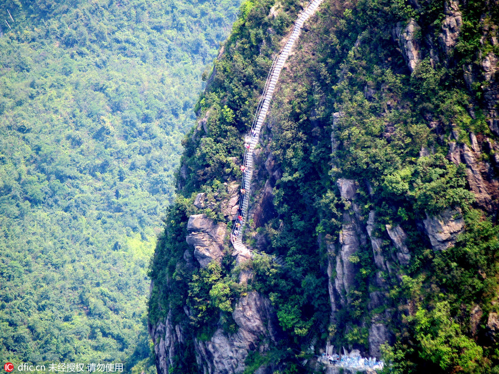 Fathers use bamboo strips to steer children on cliff walkway