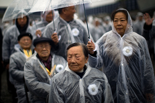 People stop and bow heads as they honor 300,000 victims of massacre