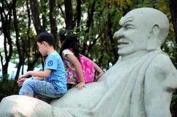 Two children sit on a sculpture