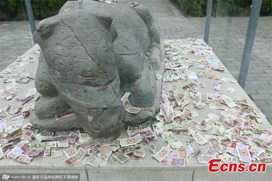 Tourists toss notes at cultural relic for luck
