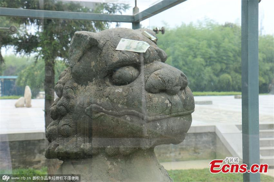 Tourists toss notes at cultural relic for luck