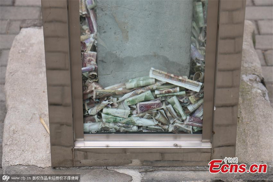 Tourists toss notes at cultural relic for luck