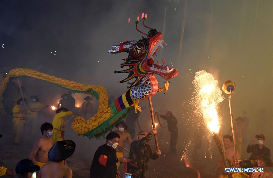 People perform dragon dance in flames of firecrackers in Guangxi