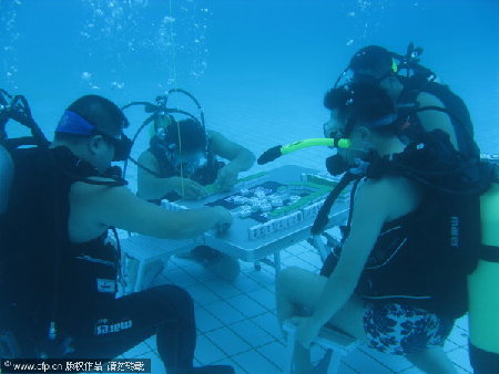 Divers play mahjong underwater to avoid the scorching weather in Xiangtan, Hunan province