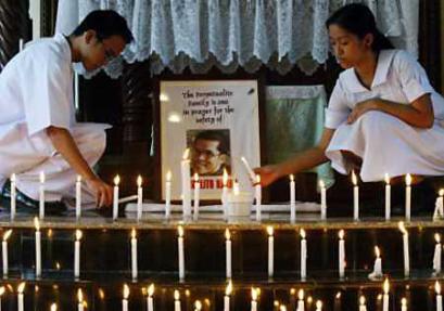 Filipino students light candles in front of the portrait of Angelito Nayan, who is held by militants in Afghanistan together with two other foreign U.N. workers, during a prayer vigil for his safe release in Las Pinas, south of Manila, November 9, 2004. Afghan kidnappers threatened to kill one of three captives if demands are not met by 0530 EST on November 9, 12 days after the U.N. workers, including Nayan, were abducted in Kabul. [Reuters]