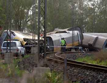 Police officers stand near the wreckage of a passenger train about 400 kilometres (250 miles) north of Brisbane November 16, 2004. The high-speed passenger train derailed on Tuesday on Australia's tropical north coast, sending carriages and passengers flying through the air and injuring 128 people, five of them seriously. [Reuters]