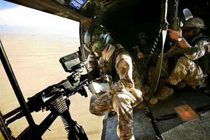 British soldiers fly in a helicopter on their way to set up a check-point in the desert near camp Dogwood 25 miles south of Baghdad on November 21, 2004. Iraq chose Jan. 30 for its first democratic election in decades, but violence in Sunni Muslim areas underlined the challenge of holding polls on time. [Reuters]