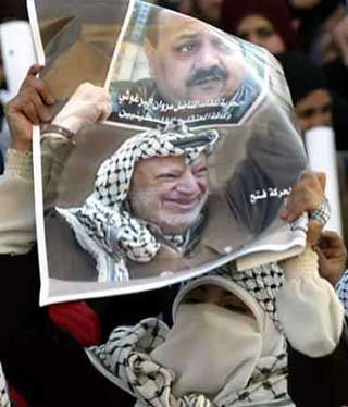 A Palestinian student holds a poster of late Palestinian President Yasser Arafat and jailed Palestinian leader Marwan Barghouthi during a rally at Al-Najah university in the West Bank city of Nablus November 30, 2004. Barghouthi decided on Wednesday to run for Palestinian president, reversing his decision to stay out of the race, Palestinian officials said. [Reuters]