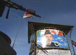 A machine gun attached to a German armoured vehicle part of International Security Assistance Force (ISAF) is seen next to a poster of Afghan President Hamid Karzai in downtown Kabul December 6, 2004. The Taliban warned on Monday its fighters will launch attacks to disrupt the swearing in ceremony of President Hamid Karzai on Tuesday. 