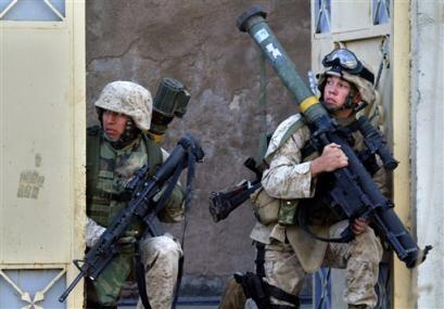 During an afternoon of sporadic battling with insurgents, U.S. Marines waiting to advance shelter inside the gateway to a home, one carrying a shoulder-launched missile, right, in Ramadi, Iraq, Monday, Dec. 20, 2004. Marines who were on a humanitarian mission to a hospital came under mortar and rocket-propelled grenade fire from insurgents, who, while fleeing, mounted several more attacks against the Marines. [AP]