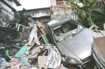  worker clears debris in the Thai resort island of Phuket, December 29, 2004. Rescuers scoured remote coastlines around the Indian Ocean for survivors of Sunday's devastating tsunami. 