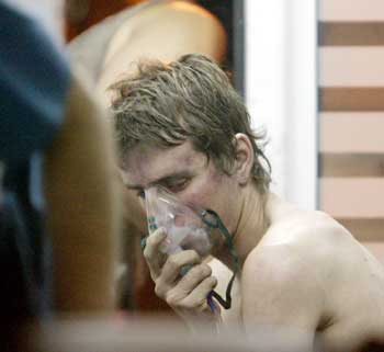 An injured man breathes with the help of an oxygen mask in an ambulance outside a nightclub in Buenos Aires, early December 31, 2004. [Reuters]