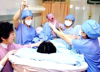Medical staffers hold a newly-born baby boy at a hospital in Beijing today. The lucky baby counted China's 1.3 billionth citizen. [xinhua]