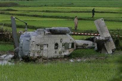 Two U.S. servicemen search for pieces of debris from a U.S. Navy Seahawk helicopter which crashed in a rice paddy less then a kilometer away from Banda Aceh's airport early Monday morning Jan 10, 2005. The crew members were all able to leave the aircraft and were airlifted to a U.S. Navy ship off the coast. [AP]