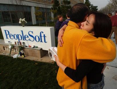 PeopleSoft employees embrace outside of the company's headquarters in Pleasanton, Calif. on Friday, Jan. 14, 2004. Oracle Corp. is expected to announce the layoff plans for its PeopleSoft takeover after the stock market closes. The purge is expected to eliminate anywhere from 4,500 to 6,000 jobs _ about 9 to 11 percent of the combined work force. (AP Photo/Marcio Jose Sanchez) 