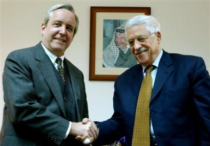 With a framed picture of late leader Yasser Arafat hanging on the wall, Palestinian Authority President Mahmoud Abbas, also known as Abu Mazen, right, shakes hands with the U.S. consul in Jerusalem David Pearce during their meeting in the West Bank city of Ramallah Tuesday Jan. 18, 2005. Abbas is heading to Gaza Strip on Tuesday for crucial cease-fire talks with militant leaders. [AP]
