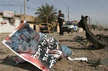 An Iraqi policeman secures the area following a car bomb explosion in front of a Shiite mosque in Baghdad, Friday, Jan 21, 2005. A car bomb exploded outside a Shiite mosque in Baghdad Friday where worshippers were celebrating a major Muslim holiday, killing at least 14 people and wounding 40, police and hospital officials said, the country's latest violence in the lead-up to this month's elections. An elections poster on the ground features the National Coalition. (AP