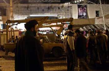 A clergyman stands in front of the mosque where a fire broke out and at least 35 worshippers were killed and more than 200 others injured, in central Tehran, Iran, Monday, Feb. 14, 2005. A poster containing, pictures of the Iranian late spritual leader, Ayatollah Khomeini, right, and supreme leader, Ayatollah Ali Khamenei hangs on the wall. (AP 