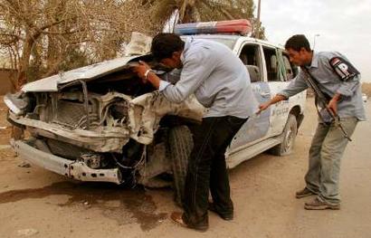 Iraqi police officers look at one of their vehicles destroyed by a roadside bomb in western Baghdad February 28, 2005. [Reuters]