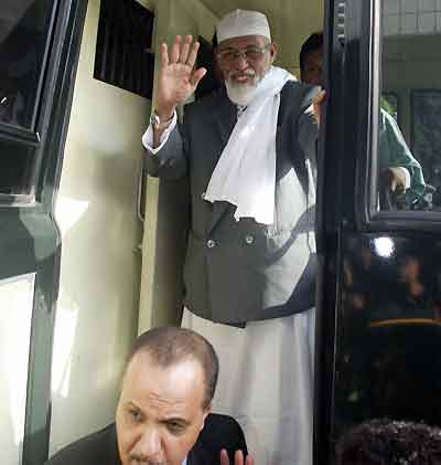 Indonesian Muslim cleric Abu Bakar Bashir (top) waves as he arrives under tight security for his trial in Jakarta March 3, 2005. A verdict is expected on Thursday in the terrorism trial of Indonesian cleric Bashir, with tight security in the courtroom and police promising "maximum force" against any outbreaks of violence. [Reuters]