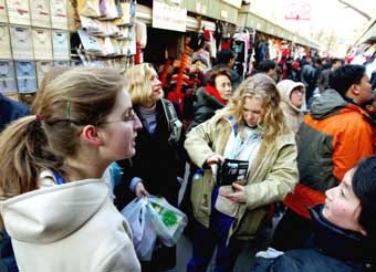 Customers, both Chinese and foreigners, are busy shopping at the Xiushui silk market, a bustling outdoor market in Beijing, December 20, 2004. The market will be closed next month due to safety considerations. [newsphoto]