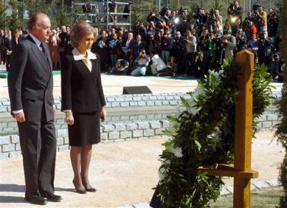 Spains King Juan Carlos and Queen Sofia stand back after placing a wreath of flowers during a five-minute silent vigil for the train bomb victims at a site in Madrid's Retiro Park Friday, March 11 2005, marking the first anniversary of the train bombings that killed 191 people and wounded more than 1,500 in Madrid, Spain. [AP/file]