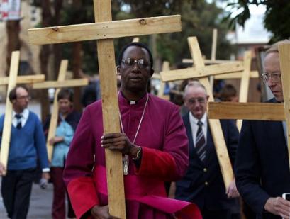 Roman Catholic Archbishop of Bulawayo Pius Ncube left and people from different church groups walk together holding crosses in the street of Bulawayo, Zimbabwe on Friday, March 25, 2005. Ncube took part in the Good Friday procession to show his solidarity for the people suffering in Zimbabwe. (AP Photo/Schalk van Zuydam)