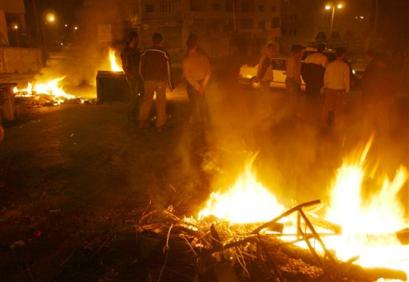 Palestinian men gather next to burning tires in a street at the West Bank city of Ramallah Thursday, March 31, 2005. A group of Palestinian militants fired Wednesday at Palestinian leader Mahmoud Abbas' West Bank headquarters while he was in the compound, but he was not injured, security officials said. (AP Photo/Nasser Nasser) 