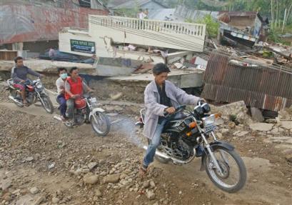 Motorcycles climb a severely damaged road, Thursday, March 31, 2005, in Gunung Sitoli on Nias Island, Indonesia. U.N. aid agencies are rushing to assist survivors of Monday's earthquake, which killed up to 1,000 people and left survivors short of food, petrol and fresh water. (AP Photo/Suzanne Plunkett)