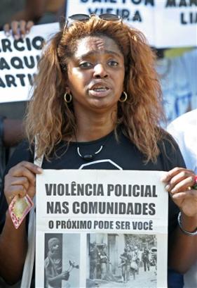 Relative of victims of a 'massacre' protest holding a poster that reads 'Police violence in our community' in front of the Sao Antonio church, in Nova Iguacu, Brazil, on Saturday, April 2, 2005. [AP]