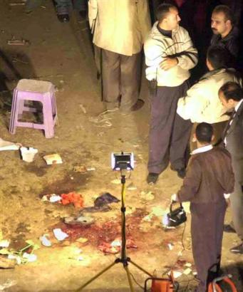 Egyptian policemen surround blood stains and debris at the site where an explosion set off by a man on a motorcycle hit an outdoor bazaar popular with tourists in Cairo's Old City on Thursday April 7, 2005, killing two people including a French woman, and wounding at least 14 others, including an American, officials said. (AP Photo/Nasser Nouri) 