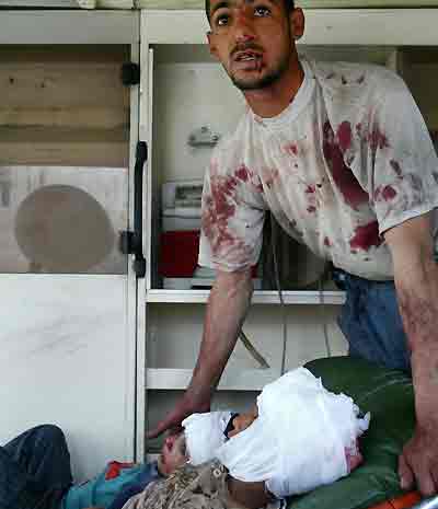 A man comforts two children who were injured by a suicide car bomb explosion in Baghdad April 14, 2005. At least 11 people were killed in twin suicide bomb blasts near an Interior Ministry building in central Baghdad on Thursday, an official at the Interior Ministry said. [Reuters]