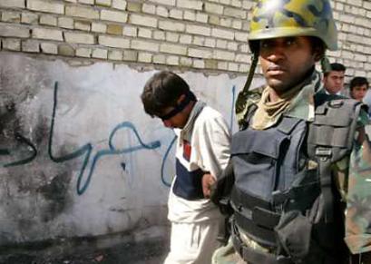 An Iraqi soldier guides a 16 year-old detainee following his arrest during a joint security operation in the town of Madaen south of Baghdad, April 18, 2005. Iraqi forces searched the town near Baghdad for evidence of dozens of Shi'ites said to have been taken hostage by Sunni militants, a claim government officials said was exaggerated for political ends. (Akram Saleh/Reuters) 